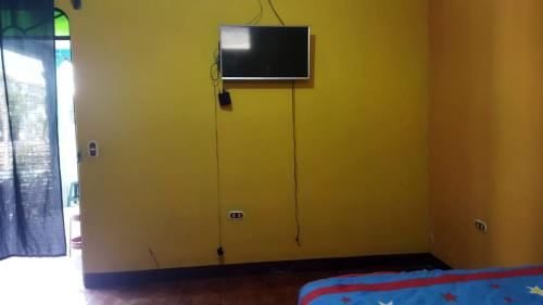 Zimmer mit einem TV an einer gelben Wand in der Unterkunft Casa Xuan in San Juan La Laguna