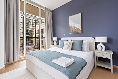 a blue bedroom with a large bed and a window at Silkhaus Luxurious 1 BDR Next to Golf Course in Abu Dhabi