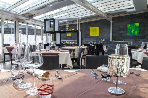 un comedor con mesas y sillas y copas de vino en Hôtel Terminus en Porrentruy
