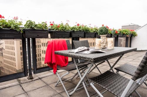 a table and chairs on a balcony with flowers at The Queen Luxury Apartments - Villa Marilyn in Luxembourg