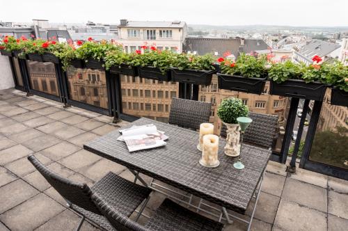 a table and chairs on a balcony with flowers at The Queen Luxury Apartments - Villa Marilyn in Luxembourg