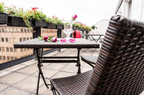 a table and chairs on a balcony with flowers at The Queen Luxury Apartments - Villa Marilyn in Luxembourg