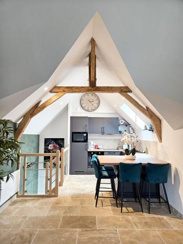 une cuisine avec une table, des chaises et une horloge dans l'établissement L'Escapade Nature et SPA, 10 mn du ZooParc de Beauval, à Saint-Romain-sur-Cher