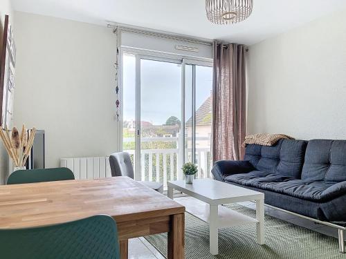 un salon avec un canapé bleu et une table dans l'établissement CABOURG - 2 PIÈCES avec Balcon et parking- Hyper Centre et Plage, à Cabourg