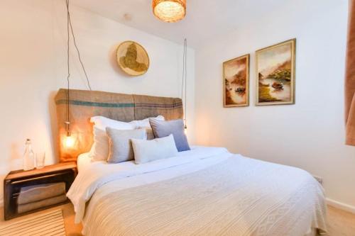 um quarto com uma cama com lençóis brancos e almofadas em NEW Street Cottage - Centre Cotswolds 3 Bed em Oaksey