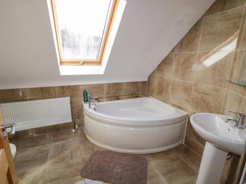 baño con bañera grande y lavamanos en Gunn's Cottage, en Killyhevlin