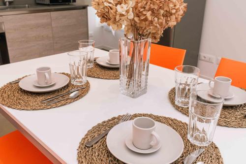 a table with plates and glasses and a vase with flowers at GOMES COMFORT HOUSE in Valeggio sul Mincio
