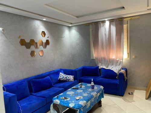 a living room with a blue couch and a table at Jolie appartement oulfa azhar in Casablanca