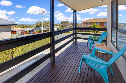 a balcony with two blue chairs and a table at Livin the Dream in Lakes Entrance