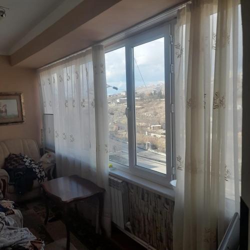een kamer met een groot raam met witte gordijnen bij Keshish guests house in Vanadzor
