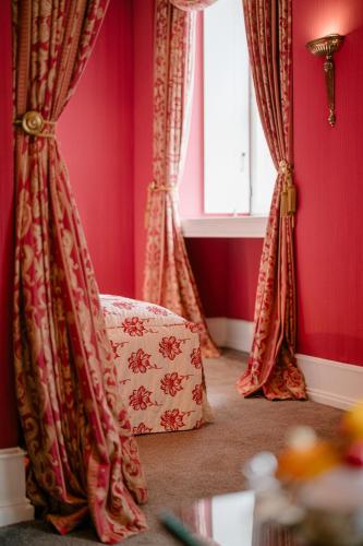 a room with red curtains and a chair with a window at Schlosshotel Hugenpoet in Essen