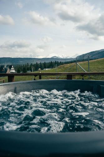 a tub of water with a view of a field at Góralski Harem Osada Glamp & Glass z Jacuzzi i Balią in Zakopane
