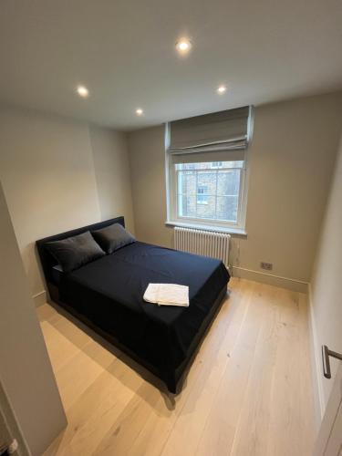 a bedroom with a black bed with a window at Stunning Portobello Road flat in London