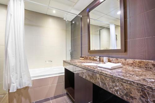 y baño con lavabo, espejo y bañera. en Silkhaus Contemporary 1 BDR Next to Golf Course, en Abu Dabi