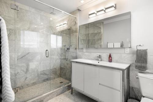 La salle de bains est pourvue d'une douche, d'un lavabo et d'un miroir. dans l'établissement Executive 2bed 3bath Townhome, James Bay/Dallas Rd. 2 Parking Spots, Hot Tub!, à Victoria