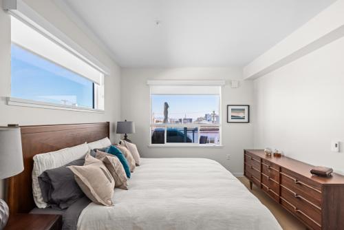 Un dormitorio con una cama grande y una ventana en Modern 1000sqft+ Condo in Sidney, Ocean Views, Parking. Walk to Shops, Restaurants! en Sidney