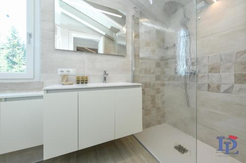 ein weißes Bad mit einem Waschbecken und einer Dusche in der Unterkunft Desenzanoloft H2o in Desenzano del Garda