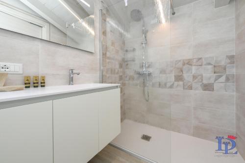 a white bathroom with a shower and a sink at DesenzanoLoft Official Partner Homes & Villas by Marriott Bonvoy - H2o inside green residence with 3 pools in Desenzano del Garda