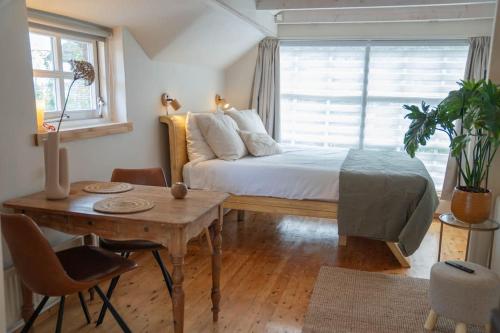 a bedroom with a bed and a table and a window at Reestdal Cottage in De Wijk