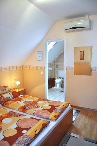 a bedroom with two beds and a bathroom at Napsugár Vendégház in Tihany