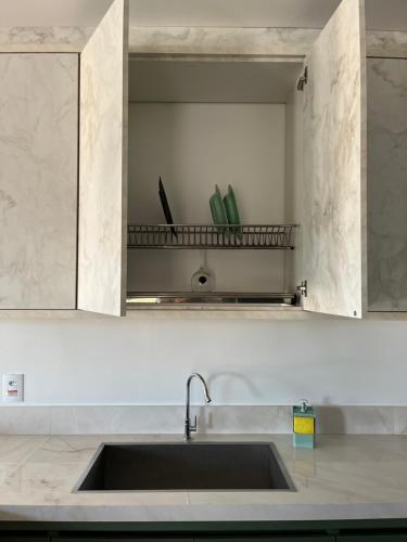 a kitchen counter with a sink and a shelf at Villa Regina in Pato Branco