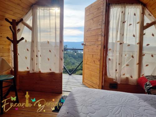 um quarto com uma cama e vista para uma varanda em Encanto Dorado em Guatavita