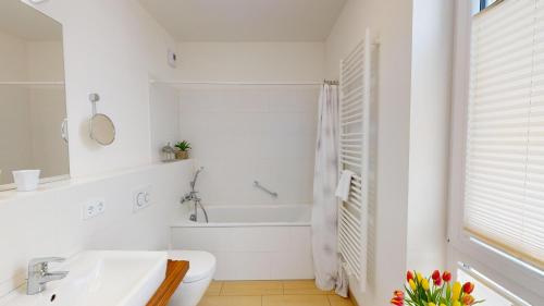 La salle de bains blanche est pourvue d'une baignoire et d'un lavabo. dans l'établissement Südkap H-02, à Pelzerhaken