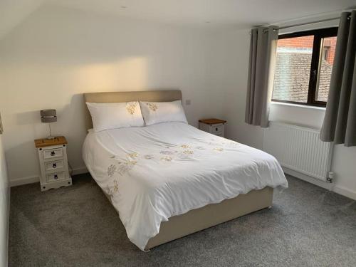 a bedroom with a bed with white sheets and a window at 1 bedroom self contained separate Annexe in Exeter in Ide