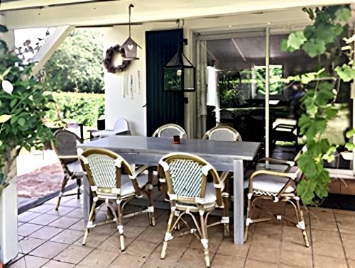 una mesa al aire libre y sillas en un patio en Villa de 3 chambres avec piscine partagee sauna et jardin clos a Ecuras, en Écuras