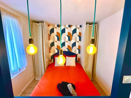 a small bedroom with a red bed with two lights at La vacancière - 308 in Rouen