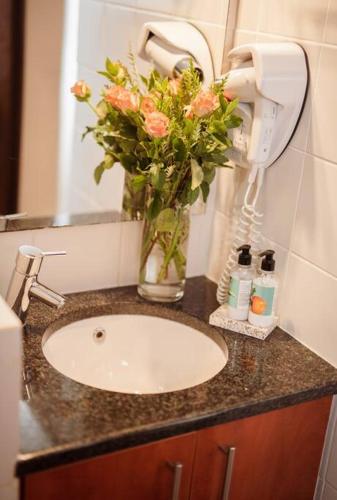 a bathroom sink with a vase with flowers in it at Apartment in central Stellenbosch in Stellenbosch