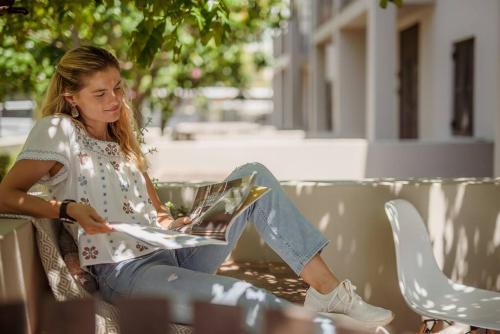 a woman sitting on a bench reading a book at Apartment in central Stellenbosch in Stellenbosch