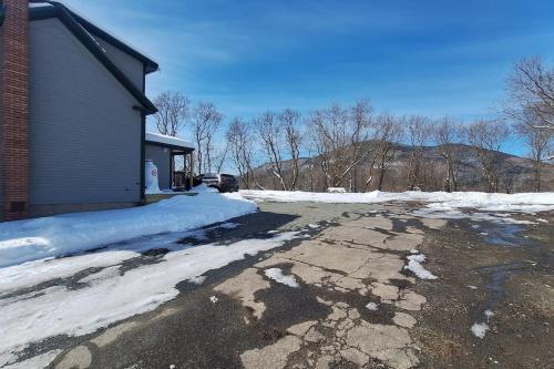a driveway covered in snow next to a house at Direct trail access/central location/Ample parking in Colebrook