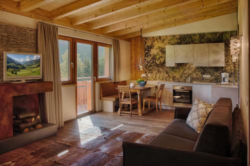 a living room with a couch and a kitchen with a table at Residence Alpenrose in San Giovanni in Val Aurina