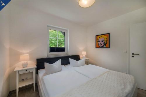 ein weißes Schlafzimmer mit einem weißen Bett und einem Fenster in der Unterkunft Villa Doris Whg 1 Merilyn in Heringsdorf