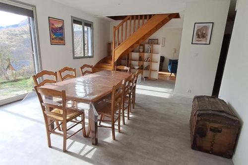 une salle à manger avec une table, des chaises et une valise dans l'établissement Maison Pyrénées - Poubeau, à Poubeau