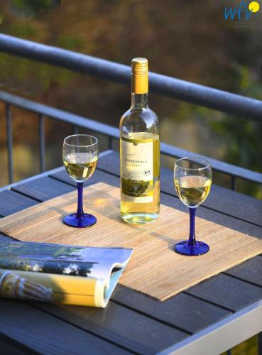a bottle of wine and two glasses on a wooden table at Haus Bahnhofstraße 11a Ferienwohnung Kleine Inselliebe in Wangerooge