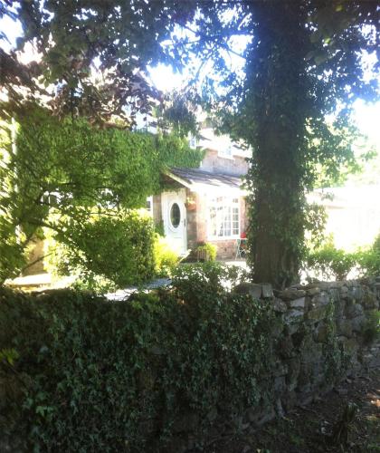 a house with a stone wall and a tree at Wye Valley near Tintern Abbey Charming cottage within farmhouse Rocklea Farm,Broadstone, Trellech Monmouthshire in Monmouth