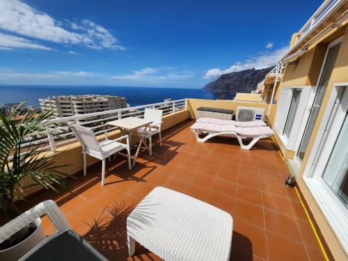 a balcony with chairs and tables and the ocean at Los Gigantes,huge terrace,sea view,air conditioning in Puerto de Santiago