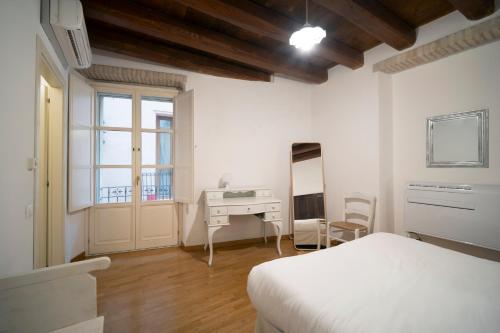 a bedroom with a bed and a desk and a window at Suite Martini al Castello in Cagliari