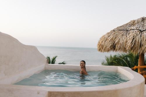 a woman in a swimming pool next to the ocean at Casa Las Tortugas Petit Beach Hotel & Spa in Holbox Island