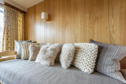 Una cama con un montón de almohadas. en Les marmottes en Courchevel