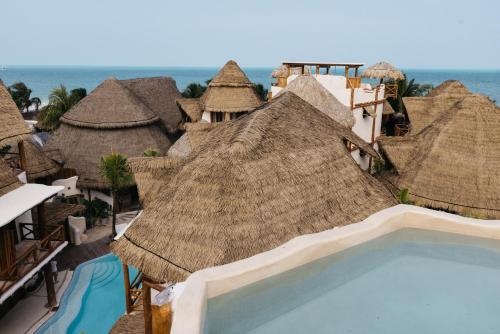 a resort with a swimming pool and some straw umbrellas at Casa Las Tortugas Petit Beach Hotel & Spa in Holbox Island