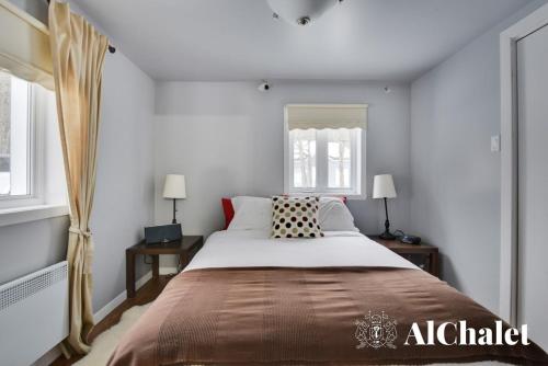 a bedroom with a large bed and two windows at Un coin pour deux in Saint-Raymond