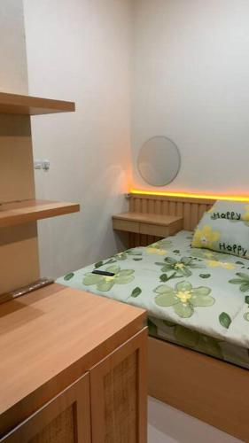a small bedroom with a bed with a green blanket at AdyneVille in Malang