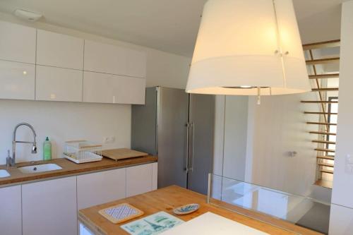 cocina con armarios blancos y mesa de madera en Maison moderne et confortable en bordure de forêt, en Poissy