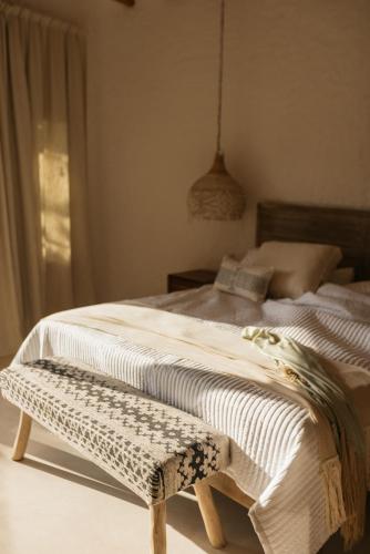 a bedroom with a bed with a bench on it at Casa Las Tortugas Petit Beach Hotel & Spa in Holbox Island