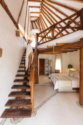 a person walking up a staircase in a bedroom at Casa Las Tortugas Petit Beach Hotel & Spa in Holbox Island