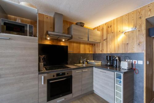 une cuisine avec des armoires en bois et un four à plaques de cuisson dans l'établissement Arc 2000 appartement type chalet, à Bourg-Saint-Maurice