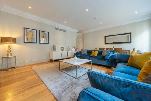 a living room with blue couches and a table at Beautiful 2-Bedroom Apartment in Mayfair in London